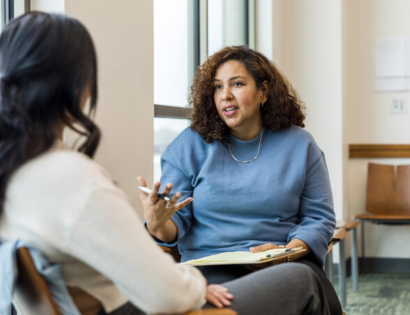 The female therapist gestures while she talks to the unrecognizeable woman about some strategies she can use at work to deescalate tough situations.